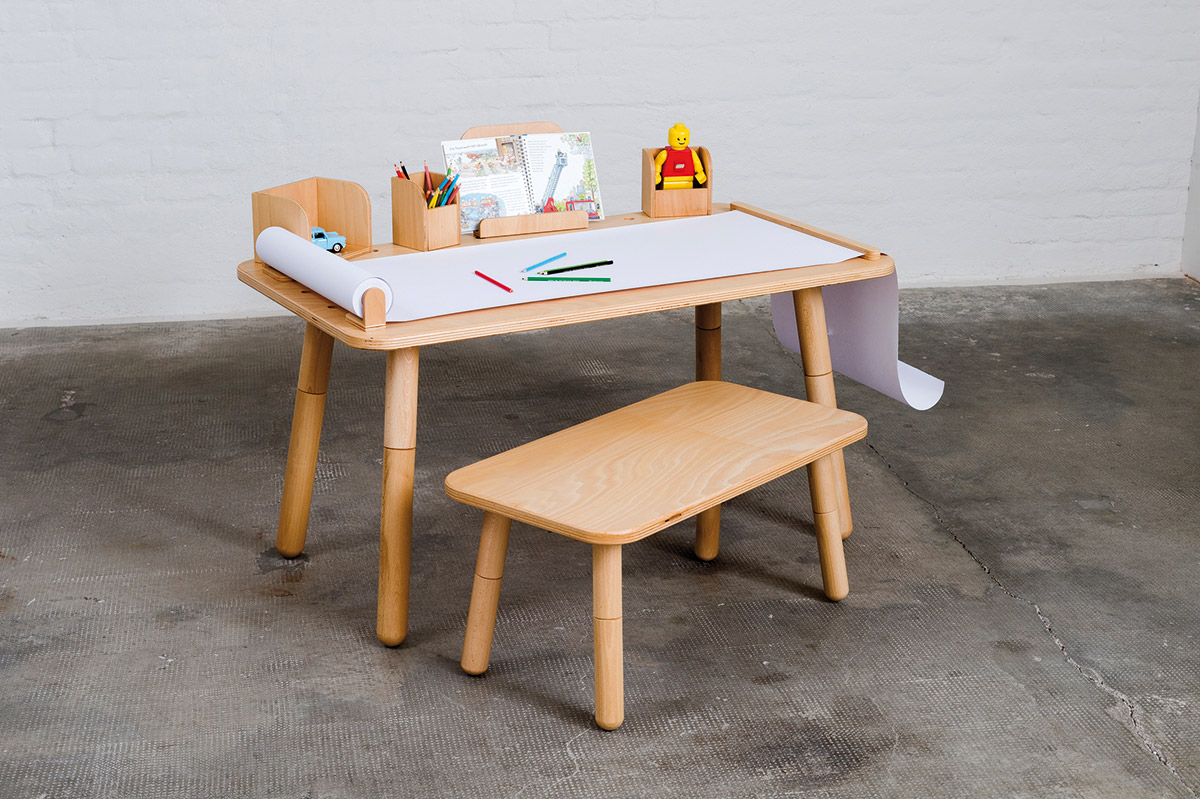 Growing Table mit einem Hocker davor und Schreibpapier mit Stiften